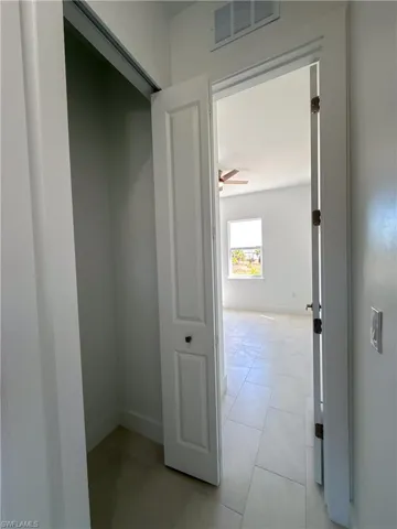 Hallway closet with baseboards and light tile patterned floors