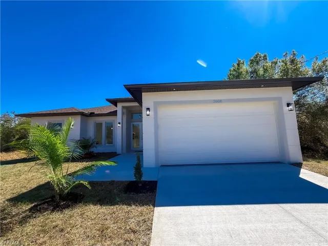 View of front facade with concrete driveway, an attached garage, and stucco siding