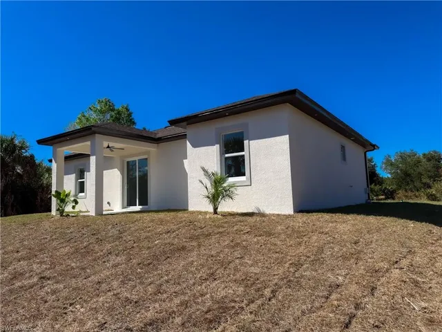 Rear view of property featuring a lawn, stucco siding, a patio area, and ceiling fan