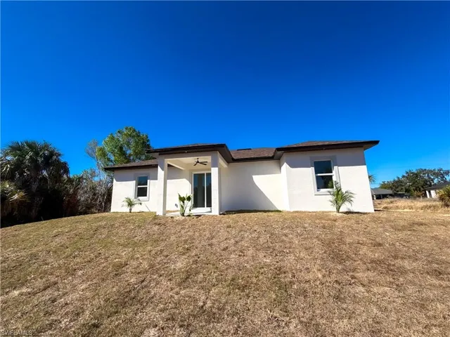 Back of house featuring stucco siding and a lawn