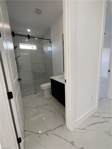 Bathroom with vanity, an enclosed shower, and toilet