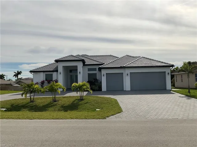 View of front of property featuring a garage and a front lawn
