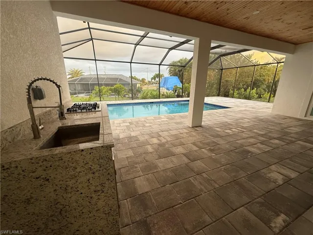 View of swimming pool featuring a lanai, sink, and a patio area