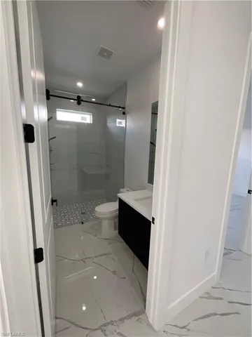 Bathroom with vanity, toilet, and a shower with shower door