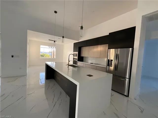 Kitchen featuring hanging light fixtures, a center island with sink, sink, and appliances with stainless steel finishes
