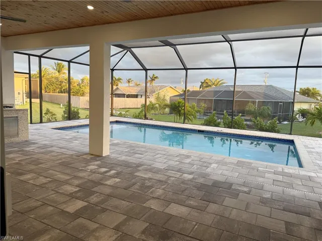 View of swimming pool featuring a patio and glass enclosure