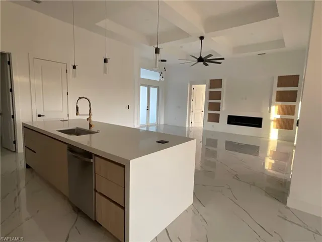 Kitchen with sink, hanging light fixtures, coffered ceiling, stainless steel dishwasher, and a kitchen island with sink