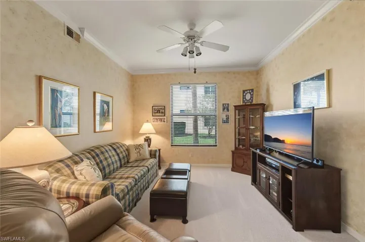 Living area featuring crown molding, ceiling fan, and light carpet