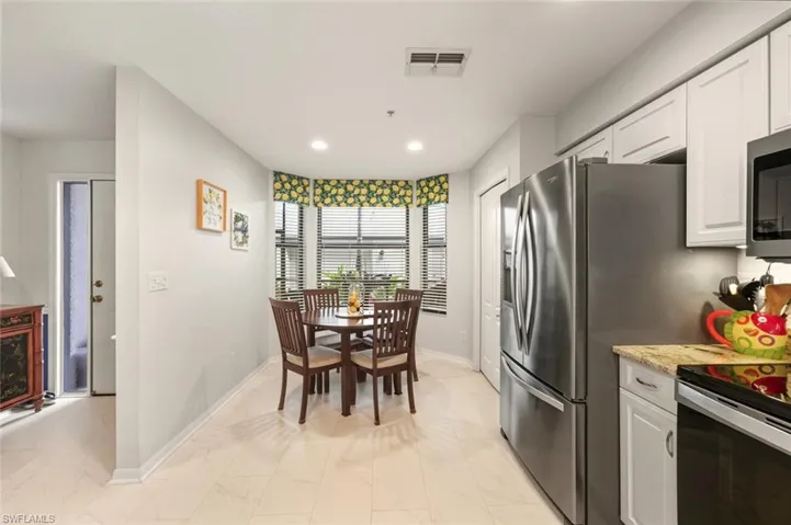 Kitchen with white cabinets, electric range oven, light stone counters, light marble finish floors, and stainless steel microwave