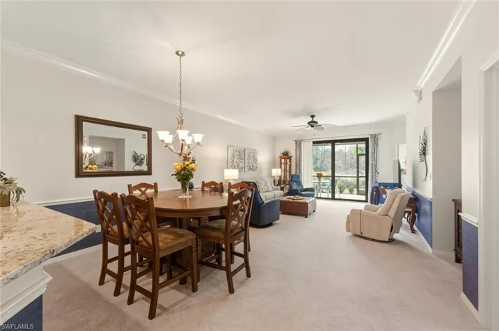 Dining space with ornamental molding, light colored carpet, ceiling fan, and a chandelier
