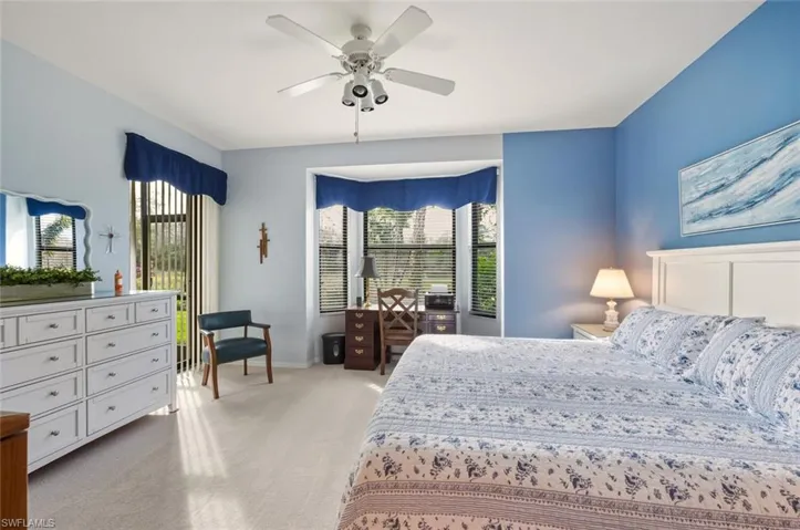 Bedroom with light colored carpet, multiple windows, and a ceiling fan