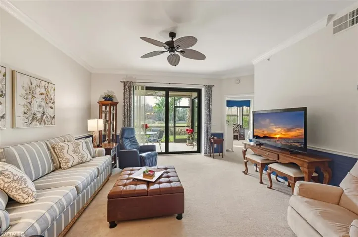 Carpeted living room with ornamental molding and a ceiling fan