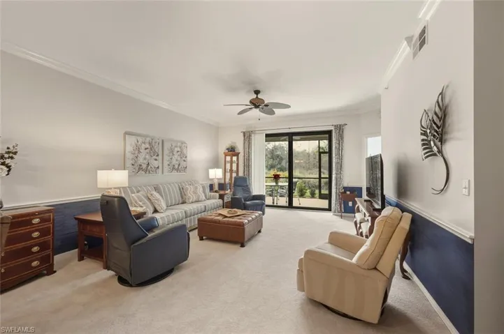 Living room featuring crown molding, a wainscoted wall, carpet flooring, and ceiling fan
