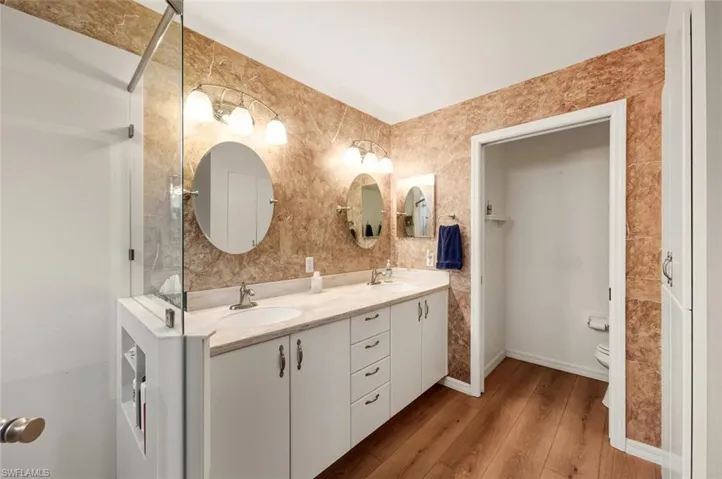 Bathroom with double vanity and light wood-style flooring