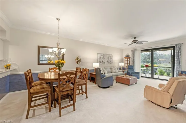 Carpeted dining space featuring crown molding, ceiling fan, and a chandelier