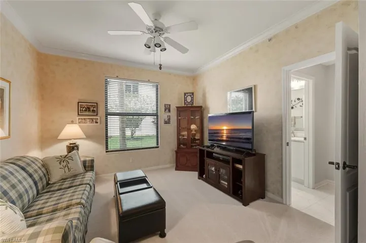 Living area featuring ornamental molding, light carpet, and a ceiling fan