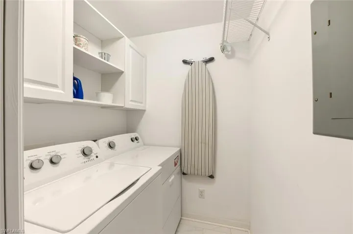 Laundry area featuring electric panel, washing machine and clothes dryer, and cabinet space