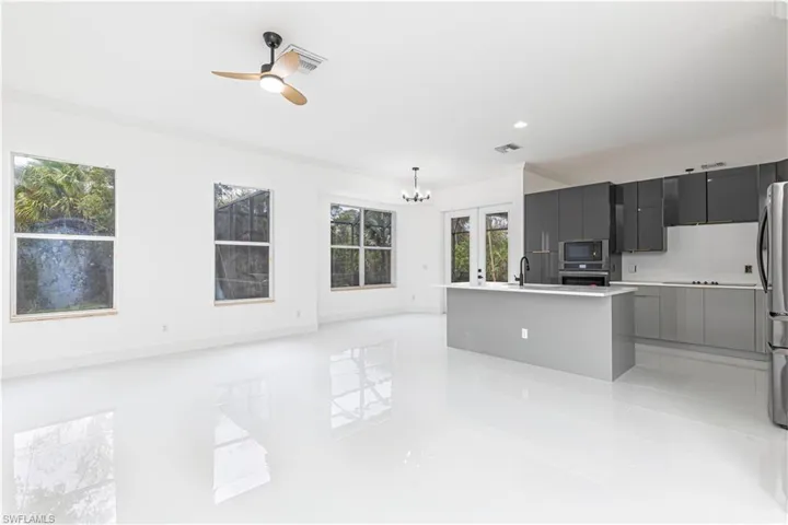 Kitchen featuring appliances with stainless steel finishes, light tile patterned flooring, modern cabinets, a sink, and light countertops