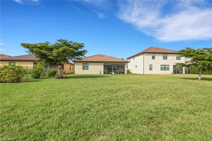 Back of house with a yard, a tile roof, and a sunroom