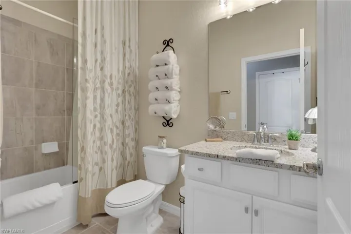 Bathroom with shower / bathtub combination with curtain, vanity, and light tile patterned floors