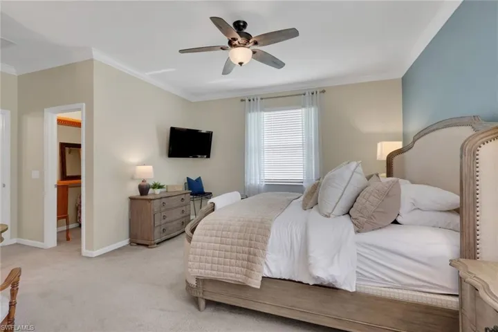 Carpeted bedroom featuring a ceiling fan and crown molding