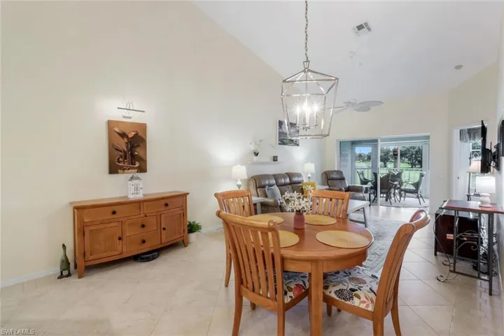 Dining space featuring high vaulted ceiling, light tile patterned floors, and a chandelier
