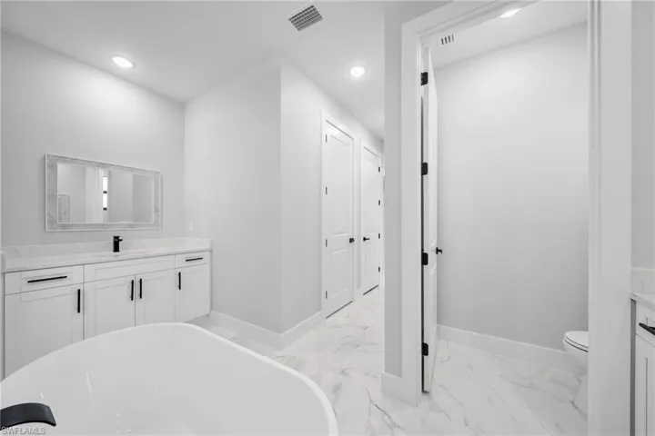 Bathroom with tile floors, a tub, vanity, and toilet