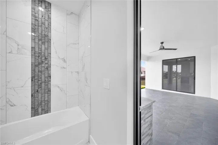 Bathroom featuring tile flooring, tiled shower / bath, and ceiling fan