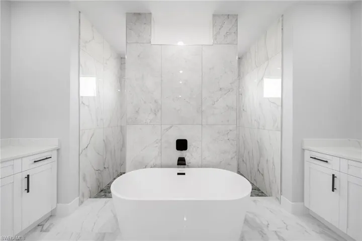 Bathroom featuring tile flooring, a bath to relax in, vanity, and tile walls