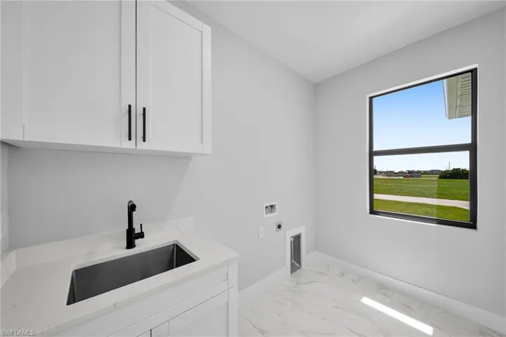 Clothes washing area with sink, washer hookup, electric dryer hookup, and cabinets
