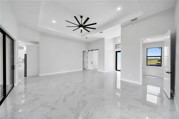 Tiled with a barn door, a tray ceiling, and ceiling fan