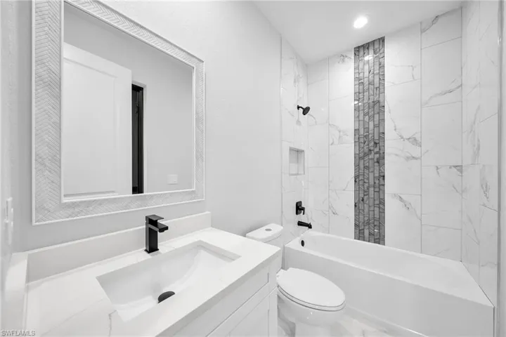 Full bathroom with tiled shower / bath, vanity, and toilet