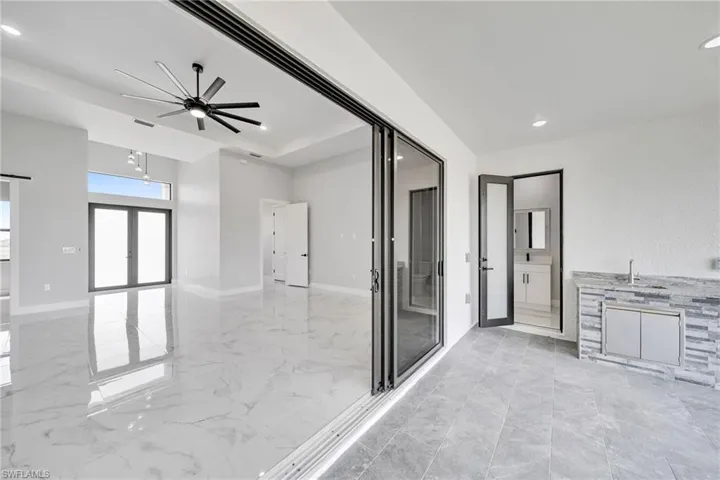 Bathroom with a tray ceiling, french doors, tile flooring, and ceiling fan