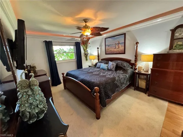 Bedroom featuring wood finished floors, ornamental molding, and a ceiling fan