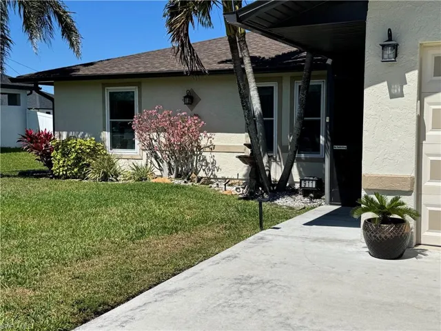 View of side of property featuring stucco siding, a shingled roof, and a yard