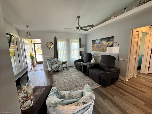 Living room with a ceiling fan, baseboards, and wood-type flooring