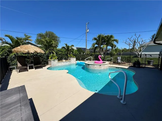View of pool with a fenced backyard, a pool with connected hot tub, and a patio