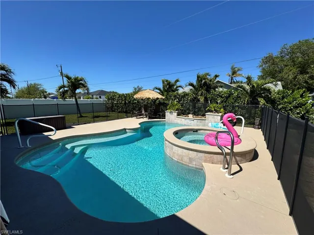 View of swimming pool with a patio area, a pool with connected hot tub, and a fenced backyard