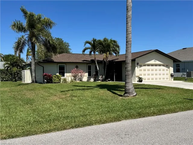 Ranch-style home with cooling unit, driveway, an attached garage, stucco siding, and a front lawn