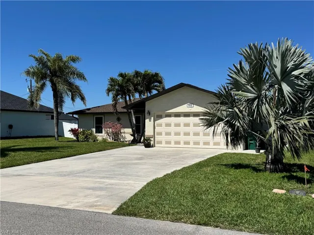 Single story home with stucco siding, driveway, a front lawn, and a garage