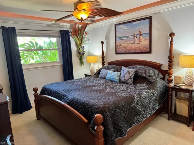 Carpeted bedroom featuring a ceiling fan and ornamental molding