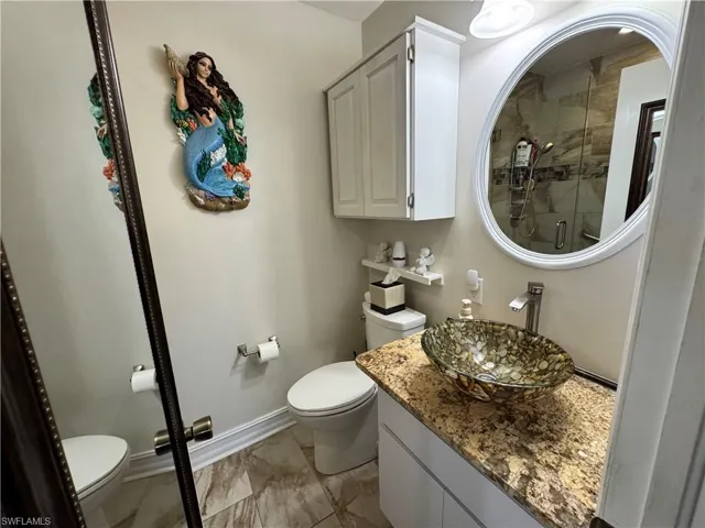 Full bathroom with vanity, toilet, baseboards, and a stall shower