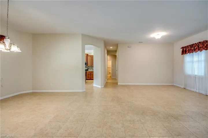 Unfurnished room featuring arched walkways, a chandelier, and light tile patterned flooring