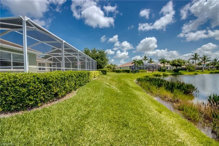 View of grassy yard with a water view and glass enclosure
