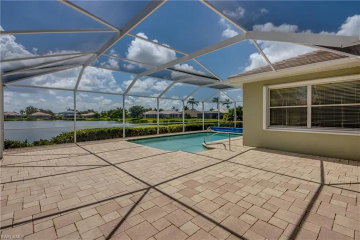 Swimming pool with a patio, a water view, and glass enclosure