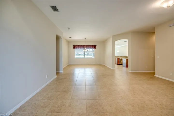 Empty room featuring arched walkways, light tile patterned floors, and a chandelier