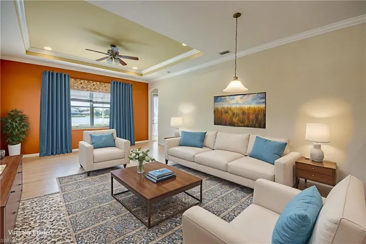 Living area with ceiling fan, crown molding, wood finished floors, a raised ceiling, and recessed lighting
