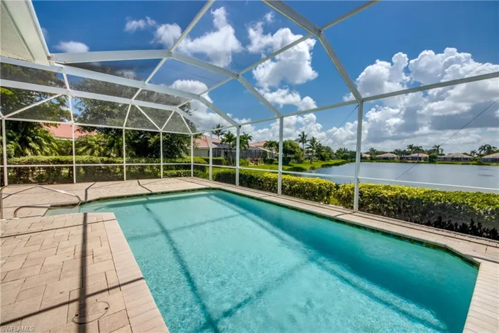 Swimming pool featuring a water view, a patio, and glass enclosure