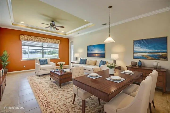 Living area featuring crown molding, ceiling fan, a raised ceiling, light tile patterned floors, and recessed lighting
