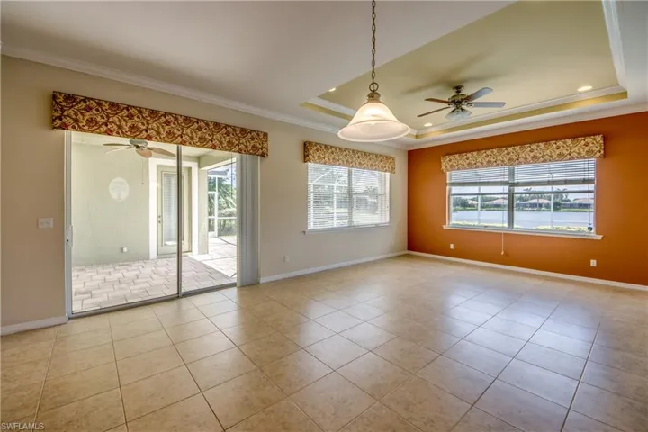 Unfurnished room featuring a ceiling fan, crown molding, tile patterned floors, and a tray ceiling